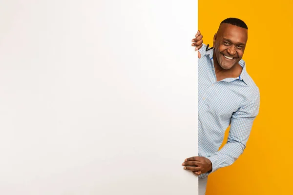 Positieve volwassen zwarte man op zoek uit blanco bordje — Stockfoto