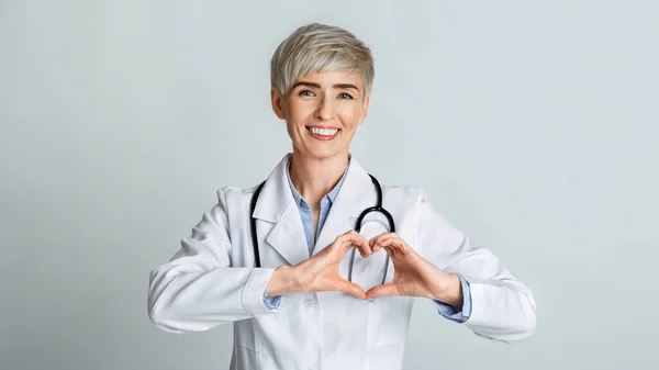 Lycklig kvinna läkare visar hjärta med händer — Stockfoto