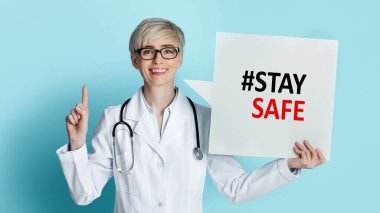 Kadın doktor yukarıyı işaret ediyor ve elinde hashtag ile konuşma balonu tutuyor mavi arka planda Kolaj