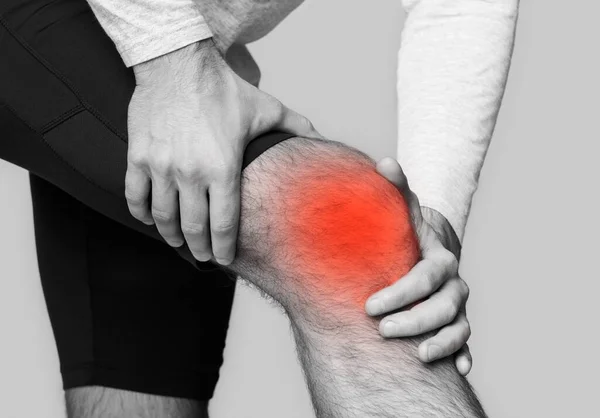 Homem com dor no joelho, destacado em vermelho — Fotografia de Stock
