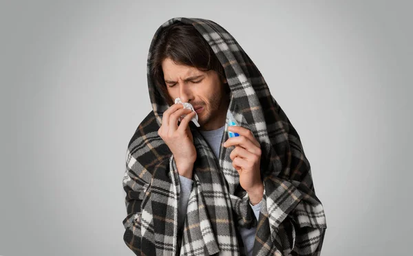 Sjuk man med servett och droppar för näsa i händerna — Stockfoto