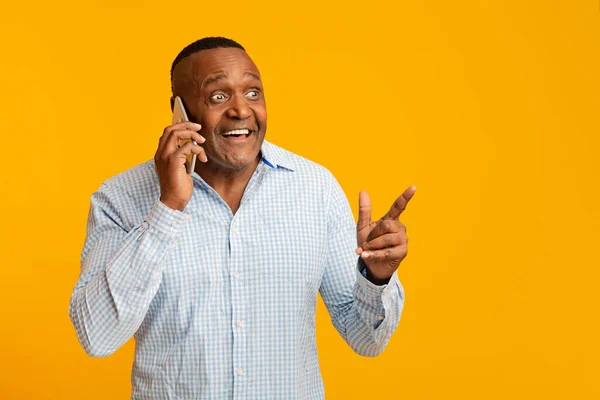 Gelukkig volwassen Afrikaanse man praten op mobiele telefoon, wijzend op vrije ruimte — Stockfoto