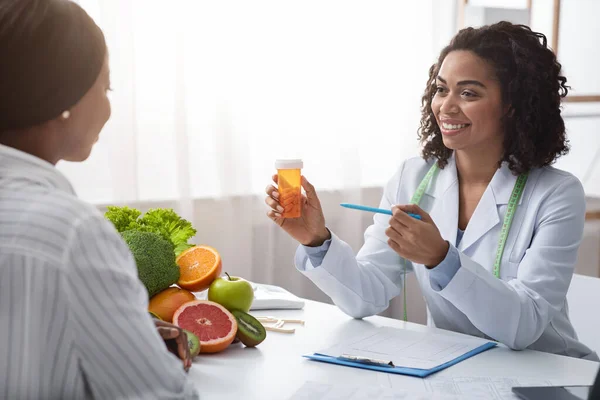 Afro medico che prescrive pillole al paziente femminile — Foto Stock