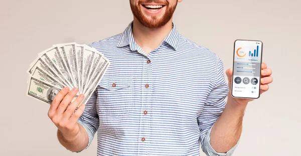 Smiling man holding money and phone with business app — Stock Photo, Image