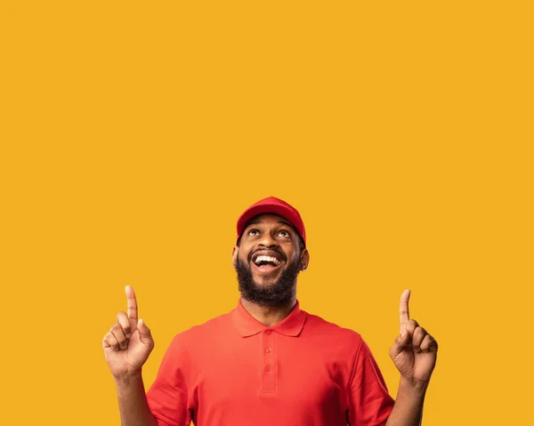 Delivery Man Pointing Fingers At Copy Space Over Yellow Background — Stock Photo, Image