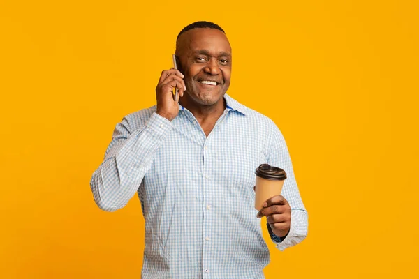 Homem americano africano maduro feliz com café falando no telefone móvel — Fotografia de Stock