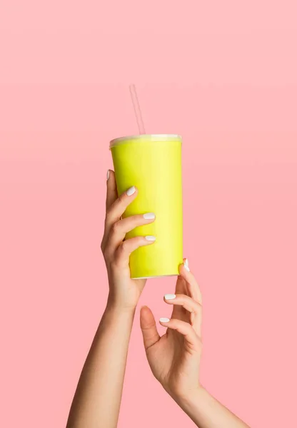 Руки женщины держат одноразовую чашку с освежающим летним напитком на розовом фоне, крупным планом. Пустое пространство для дизайна — стоковое фото