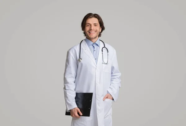 Портрет позитивного молодого терапевта с медицинской картой в руках — стоковое фото