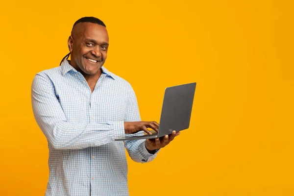 Volwassen afrikaanse amerikaanse man werken op laptop online — Stockfoto
