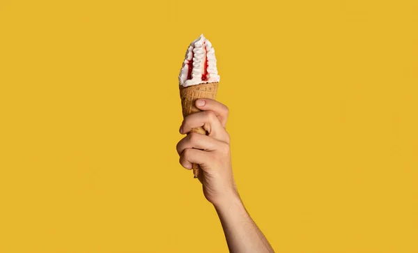 Millennial cara segurando saboroso sorvete com cobertura de frutas em cone de waffle, fundo laranja, close-up. Panorama — Fotografia de Stock