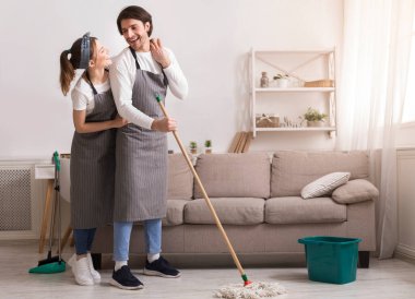 Neşeli genç çift bahar temizliği yapıyor, yerleri paspaslıyor ve sarılıyorlar.