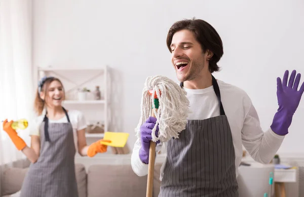 Serviço de limpeza jouful. feliz jovem casal se divertindo enquanto limpeza casa juntos — Fotografia de Stock