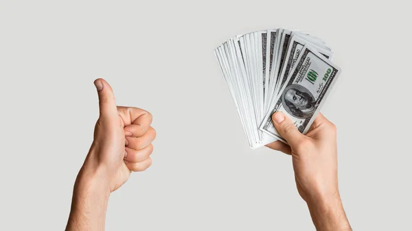 Primer plano del hombre exitoso sosteniendo ventilador de dinero y mostrando el gesto de pulgar hacia arriba sobre fondo gris claro, panorama — Foto de Stock