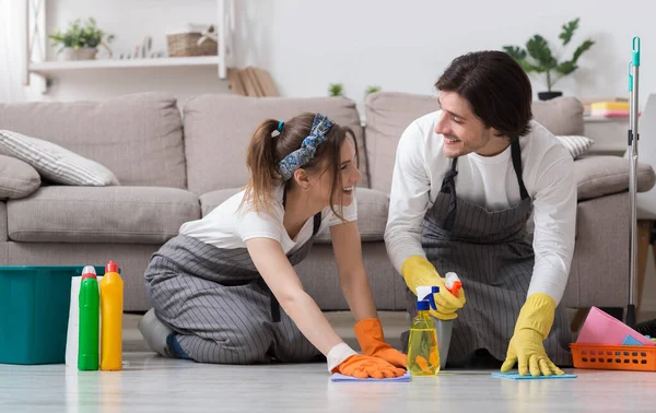 Casal feliz limpando seu apartamento juntos, lavando chão com detergentes — Fotografia de Stock