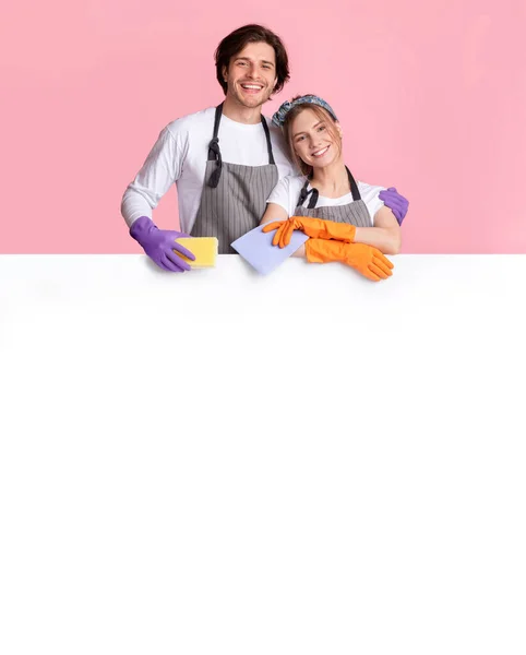 Pareja feliz de trabajadores de servicio de limpieza apoyados en la Junta de Publicidad Blanca — Foto de Stock