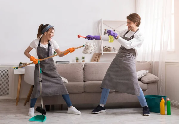 Divertimento doméstico. Jovens cônjuges brincando juntos durante a limpeza da primavera em casa — Fotografia de Stock