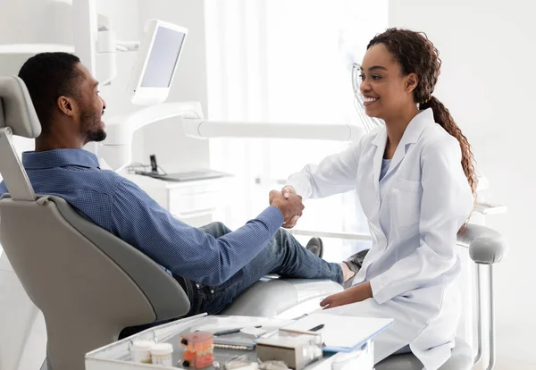 Friendly african woman dentist shaking male patient hand — Stock Photo, Image