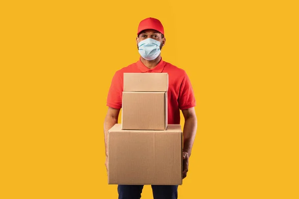 African Courier Holding Boxes Posing On Yellow Background Wearing Mask — Stock Photo, Image