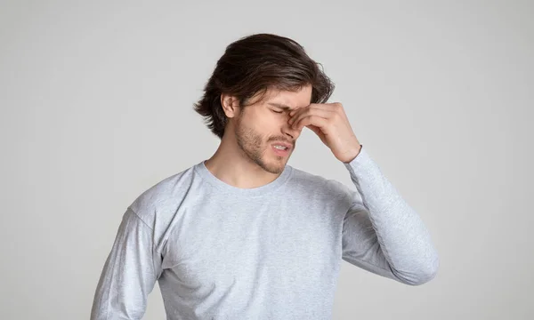 Hübscher Kerl hält Nasenbrücke und leidet unter Schmerzen — Stockfoto