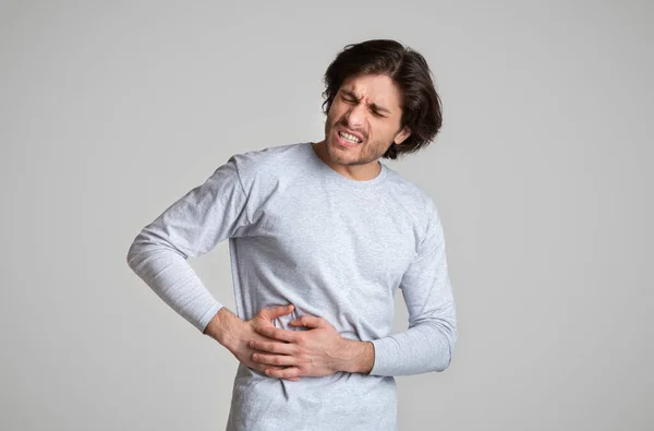 Liver pain. Guy holds hands on his side — Stock Photo, Image