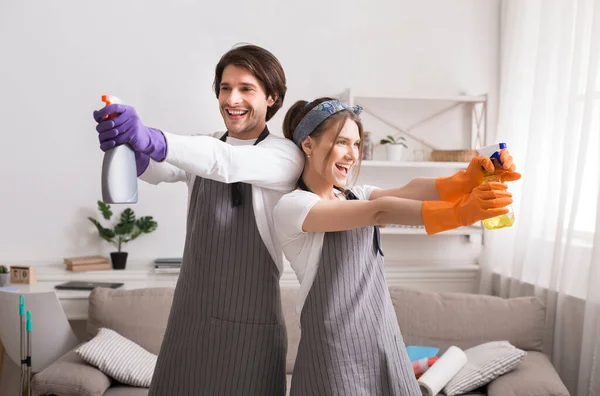 Grappig jong stel gek tijdens het schoonmaken appartement, gericht met wasmiddel sproeiers — Stockfoto