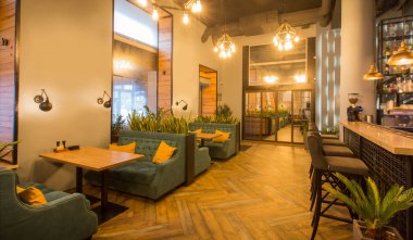 Açık renkli duvarlar ve şık restoran tasarımında yeşil mobilyalar.
