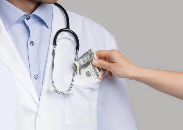 Corrupção no Setor de Saúde. Paciente irreconhecível colocando dinheiro no bolso dos médicos — Fotografia de Stock