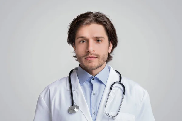 Retrato de bonito jovem médico vestindo casaco médico e estetoscópio — Fotografia de Stock