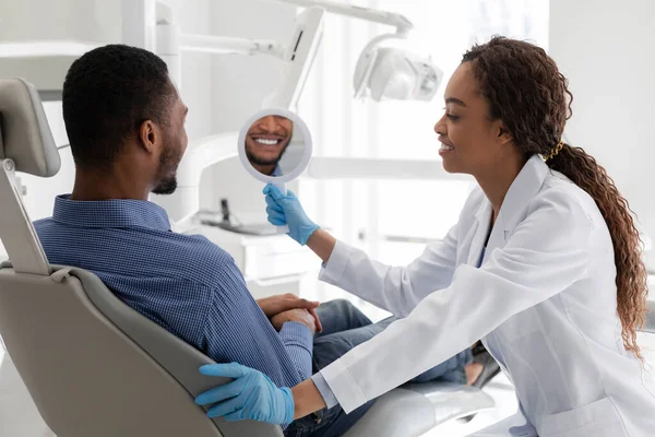 Dentista e paciente verificando sorriso no espelho após o procedimento de clareamento — Fotografia de Stock