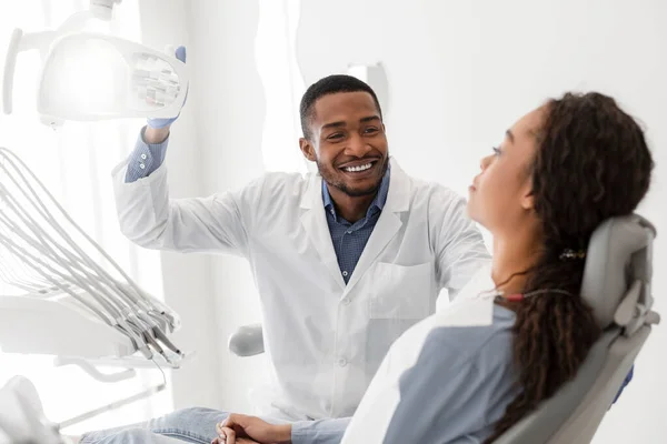 Χαρούμενος μαύρος οδοντίατρος ενεργοποιεί τον εξοπλισμό πριν το check up — Φωτογραφία Αρχείου
