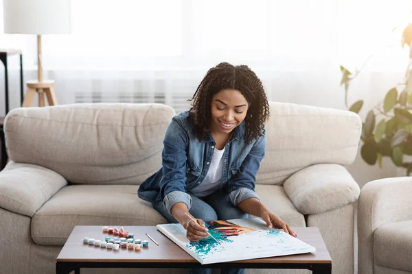 Junge schwarze Frau zeichnet Bild für Bild mit Zahlen auf Leinwand zu Hause — Stockfoto