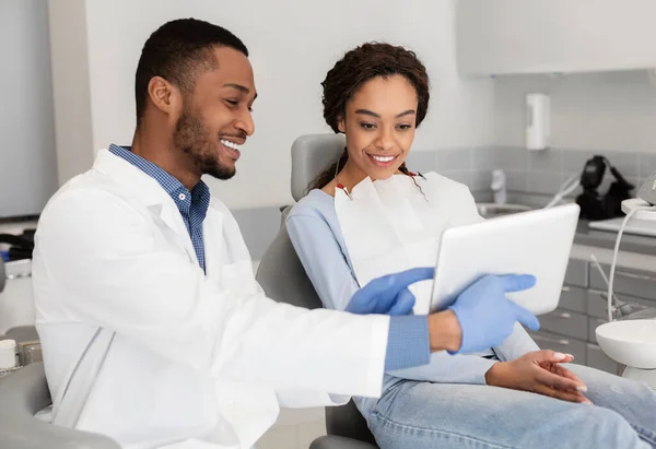 Mutlu dişçi ve kadın hasta dijital tablet ekranına bakıyor. — Stok fotoğraf