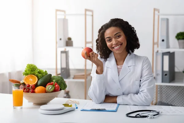 Красивая веселая женщина-диетолог держит яблоко в руке — стоковое фото