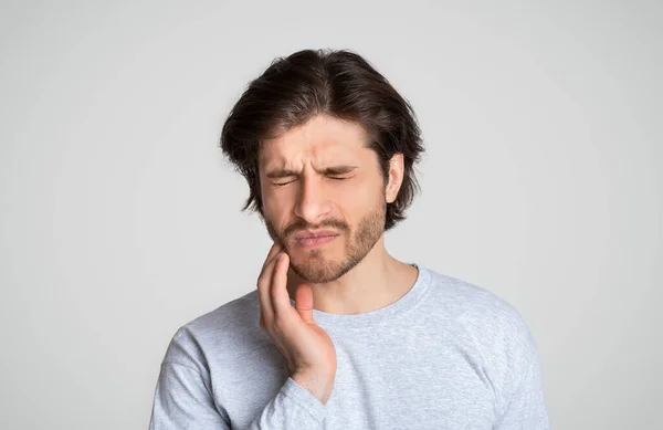 Un tizio che tocca la faccia. Uomo sensazione di forti problemi dentali — Foto Stock
