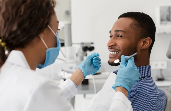 Jovem africano sorrindo para sua dentista feminina — Fotografia de Stock