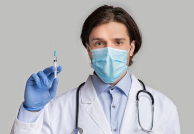 Covid-19 aşısı. Elinde şırınga olan Tıbbi Maskeli Erkek Doktor