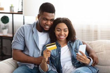 Siyah çift internetten akıllı telefon ve kredi kartı kullanıyor.