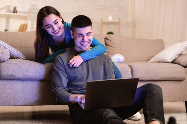 Šťastný pár pomocí PC sedí v obývacím pokoji — Stock fotografie