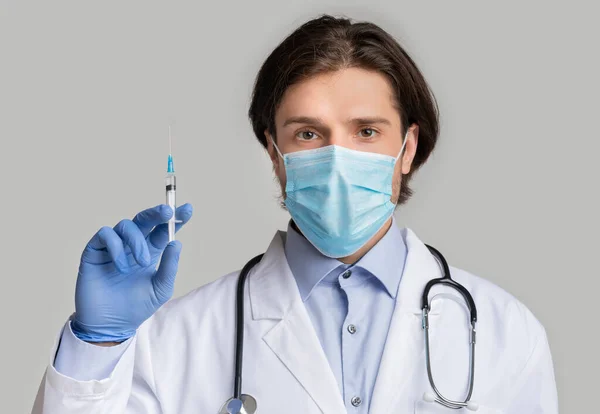 Covid-19 Vaccine. Mužský lékař v lékařské masce se stříkačkou v rukou — Stock fotografie