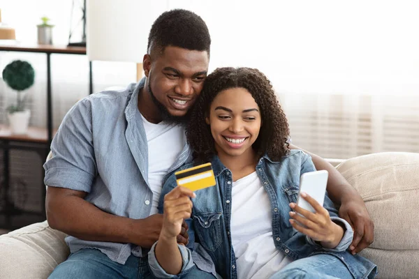 Couple noir achetant en ligne, en utilisant smartphone et carte de crédit à la maison — Photo