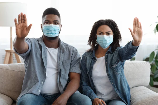 Joven pareja negra en máscaras protectoras mostrando gesto de stop en casa —  Fotos de Stock