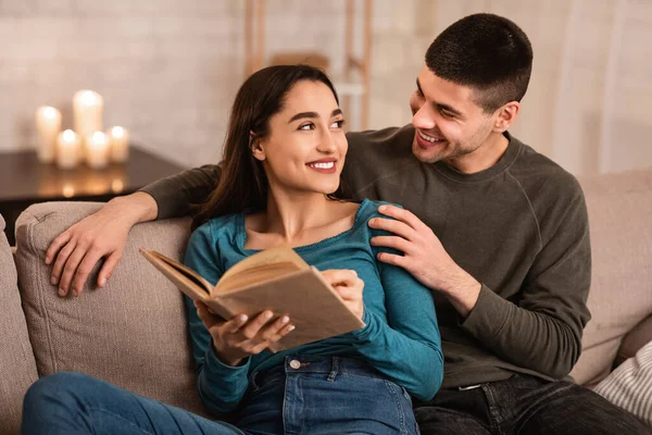 Casal sentado no sofá leitura livro juntos — Fotografia de Stock