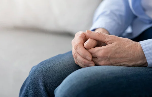 Starzenie się i emerytura. Zbliżenie rąk starszej kobiety siedzącej na kanapie — Zdjęcie stockowe