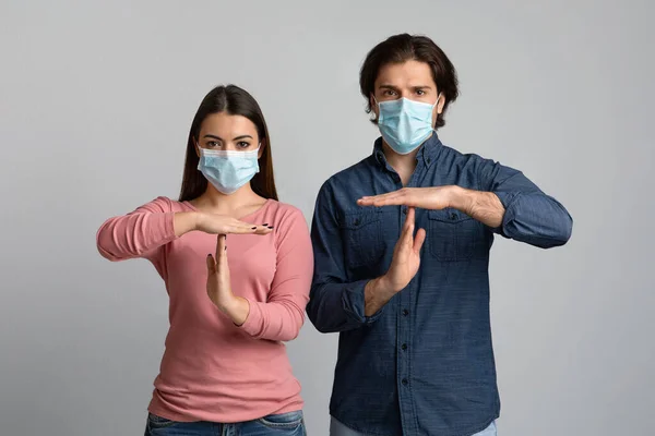 Σταμάτα την Πανδημία. Σοβαρό Millennial Ζευγάρι Φορώντας Ιατρικές Μάσκες Εμφάνιση Χρονικής Χειρονομίας — Φωτογραφία Αρχείου