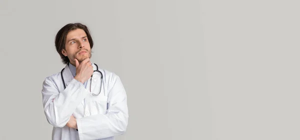 Pensive jonge dokter aanraken kin en kijken naar kopieerruimte — Stockfoto