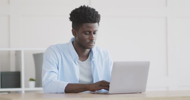 Νεαρός Αφροαμερικάνος που εργάζεται σε φορητό υπολογιστή στο σπίτι — Αρχείο Βίντεο