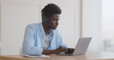 Milenyum Afrikalı adam müzik dinliyor ve dizüstü bilgisayarında daktilo yazıyor.