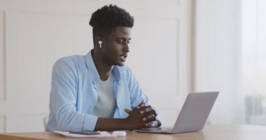 Genç Afrikalı çalışan iş arkadaşlarıyla görüntülü konuşma yapıyor.