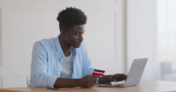 Tipo africano feliz entrando dados de cartão de crédito no site do laptop — Vídeo de Stock