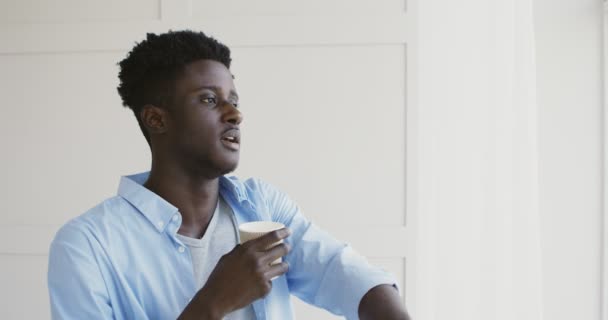 Joven afroamericano disfrutando de la vista de la ciudad a través de la ventana — Vídeos de Stock